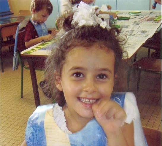 A young child with curly hair smiles, surrounded by handwritten text highlighting their positive qualities.