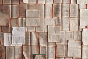 Pages de livres ouverts disposées de manière aléatoire, formant un collage textuel riche.