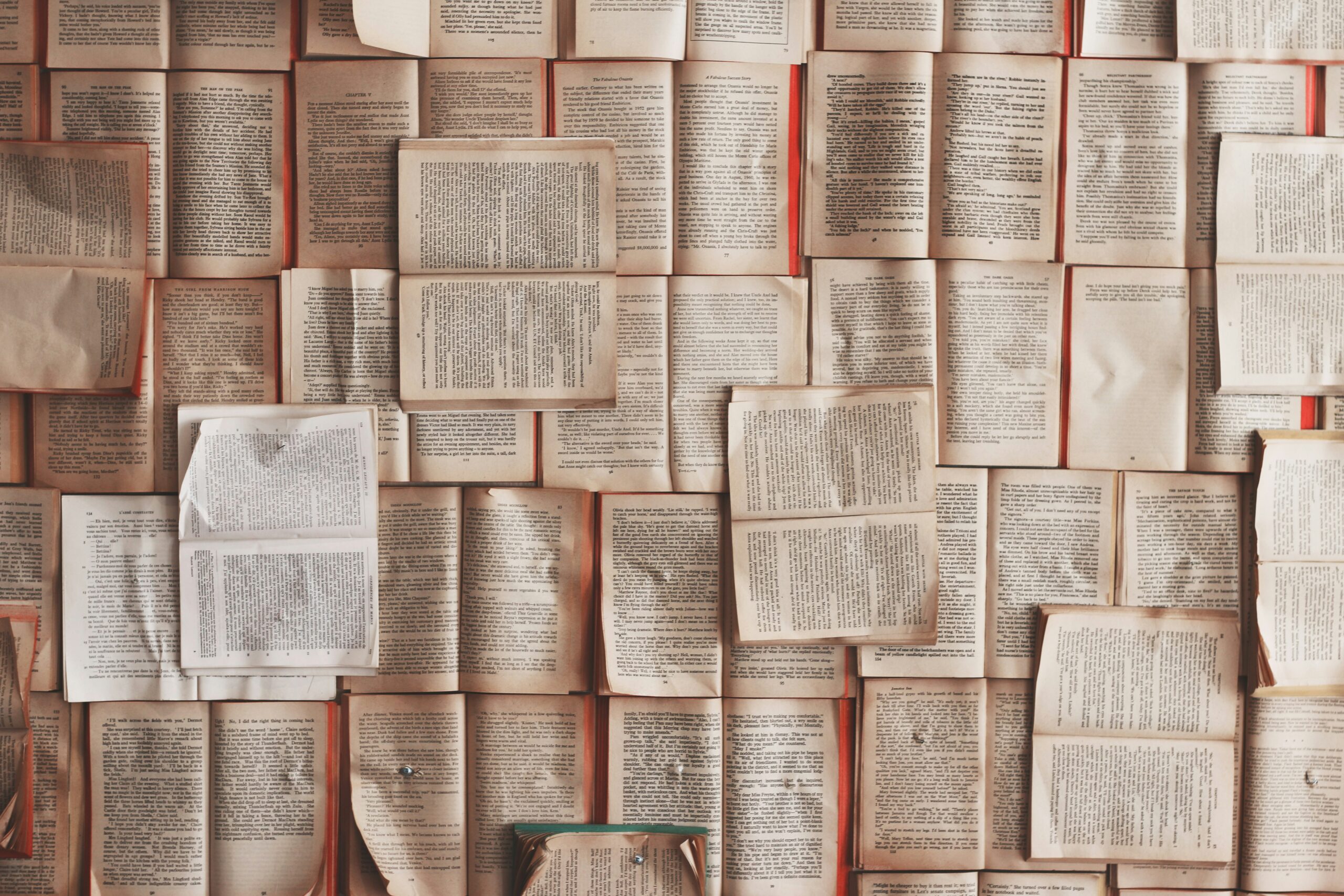 Pages de livres ouverts disposées de manière aléatoire, formant un collage textuel riche.